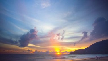 Güneşten gelen ışık ışınları renkli bulutlara nüfuz etti. Muhteşem sarı güneş adanın arkasından doğmaya başladı.. 