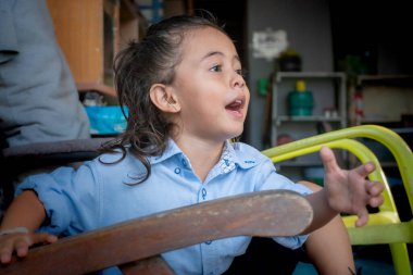 Uzun saçlı, mutlu bir şekilde gülümseyen sevimli çocuk mavi bir tişört giyiyordu. O, büyük bir sırıtış gösterirken gözleri sevinçle parladı. Kaygısız ve neşeli görünüyordu.. 