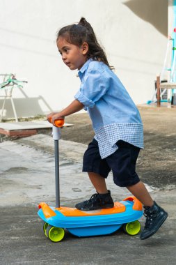 Uzun saçlı, scooter süren sevimli bir çocuğun gözlerinde yaramaz bir parıltı vardı. Açık mavi bir gömlek ve bir şort giyiyordu. Scooter 'ı renkli çıkartmalarla süslenmiş..