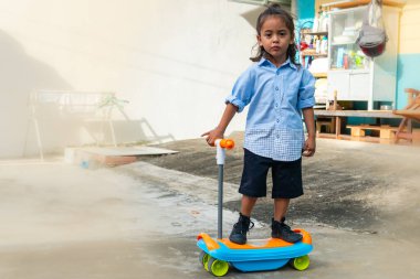 Uzun saçlı, scooter süren sevimli bir çocuğun gözlerinde yaramaz bir parıltı vardı. Açık mavi bir gömlek ve bir şort giyiyordu. Scooter 'ı renkli çıkartmalarla süslenmiş..