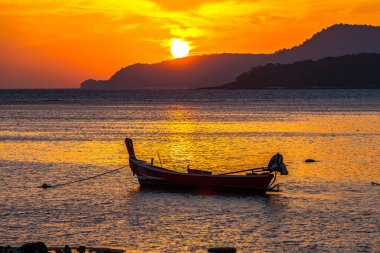 Adanın üzerinde güneşin doğuşu, altın denizdeki balıkçı teknesinin parkı..
