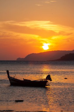 Adanın üzerinde güneşin doğuşu, altın denizdeki balıkçı teknesinin parkı..
