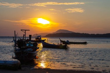 Adanın yukarısında güneşin doğuşu inanılmaz sarı gökyüzü, altın denize park eden balıkçı tekneleri