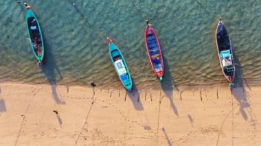 Alçak gelgit sırasında havadan görünen balıkçı tekneleri sahile park ediyor. İnsanlar kumsalda hava manzarasından yürüyorlar. Güzel balıkçı tekneleri kıyıya demir attı..