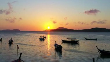 Balıkçı teknelerinin üzerindeki hava manzarası suda güzel bir yansıma yaratıyor. Denizdeki güzel güneş ışığının manzaralı yansıması Phuket denizinde yüzen balıkçı tekneleri.