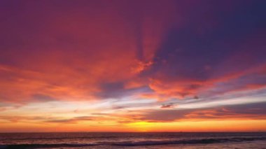 Sahildeki güzel gökyüzünün hava manzaralı yansıması. Günbatımına genellikle renkli bulutlar eşlik eder. Deniz üzerinde çarpıcı kızıl gün batımı. Video 4K Nature Yüksek kalite video.