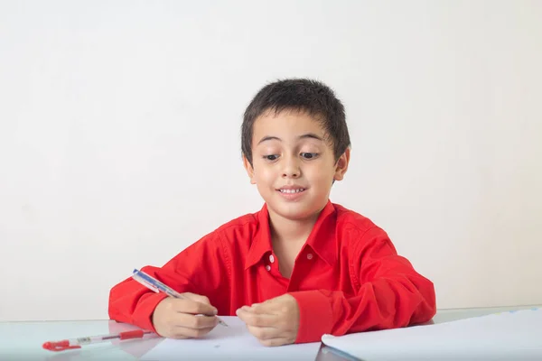 Cute Boy Red Shirt Sitting Writing Doing Homework Studio Portrait — Stock Photo, Image