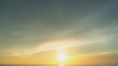 Zaman atlamalı bulutlar gün batımında denizin üzerinde yüzerler. Batan güneşin aydınlattığı bulutlar güzel ve sakin bir atmosfer yaratıyor. - Anın güzelliği nefesini keser.