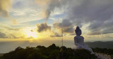 Havadan bakıldığında Phuket Büyük Buda 'nın arkasındaki bulutların arasından altın bir güneş parlıyor ve onu altın ışığıyla aydınlatıyor. Büyük Buda Phuket adasının tepesine inşa edildi..