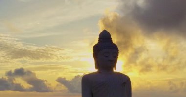 Havadan bakıldığında Phuket Büyük Buda 'nın arkasındaki bulutların arasından altın bir güneş parlıyor ve onu altın ışığıyla aydınlatıyor. Büyük Buda Phuket adasının tepesine inşa edildi..