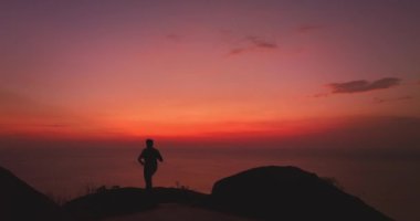 Kayalıklarda selfie çeken bir adam kızıl günbatımında parlak kırmızı gökyüzü