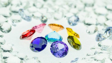 Değişik boyutlarda renkli elmaslar beyaz elmasların arka planında bir merkez daireye yerleştirilir.