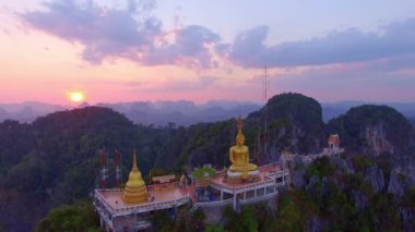 Tayland, Krabi 'deki yüksek dağın tepesindeki altın Buda heykelinin gün batımı manzarası