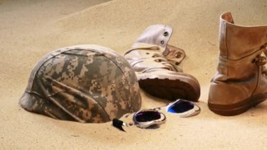 Bir askerin üniformasının parçaları kumda yatıyordu. Savaş sonrası harabeler..