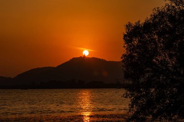 Phuket, Tayland 'da Büyük Buda heykeli üzerinde gün batımı. Büyük Buda adanın en önemli simgelerinden biridir. Günbatımı arkaplanında renkli kırmızı gökyüzü.