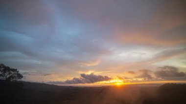 Gün batımında dağın tepelerini kaplayan sisin hızlandırılmış videosu