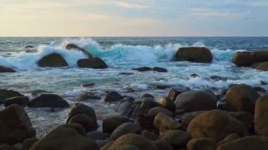 Altın güneş ışığı altındaki dalgaların videosu büyük kayalara çarptı.