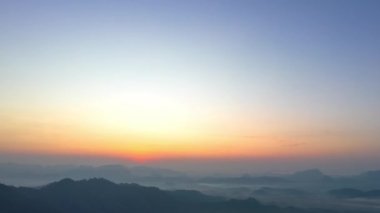 Phang Nga Vadisi 'nin dağ sırasındaki altın gün doğumu. Güneş vadideki sislerin arasından parlıyordu. Gökyüzünden gelen sarı ışık sisli vadiyi aydınlatıyordu..
