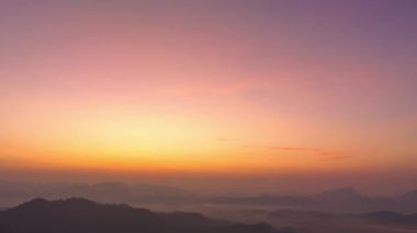 Phang Nga Vadisi 'nin dağ sırasındaki altın gün doğumu. Güneş vadideki sislerin arasından parlıyordu. Gökyüzünden gelen sarı ışık sisli vadiyi aydınlatıyordu..