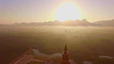 Güneşin ışınları, dağın zirvelerinden altın pagoda 'ya ışıldıyor altın pagoda güneşten gelen ışığı yansıtıyor ve sisli arka planda sarı ışık parlıyor..