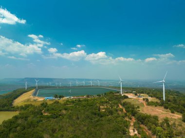 Lam Takong Barajı, Nakhon Ratchasima, Tayland 'daki dağın tepesindeki rüzgar türbinlerinin üstündeki mavi gökyüzündeki beyaz bulutların hava görüntüsü. Rüzgar enerjisi elektrik üretir. Temiz enerji.