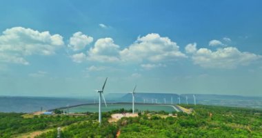 Lamtakong Barajı, Nakhon Ratchasima, Tayland 'da, dağdaki rüzgar türbinlerinin üzerinde mavi gökyüzünde yüzen beyaz bulutların hava görüntüsü. Rüzgar enerjisi elektrik üretir. Temiz enerji