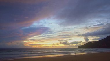Gün batımında denizin üstünde çarpıcı renkli bulutlu bir görüntü.