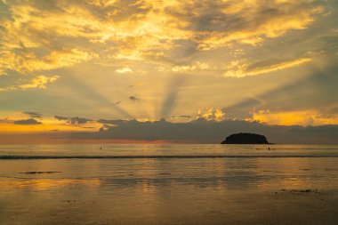 Gün batımı bulutları arasında inanılmaz altın bir ışık. Renkli romantik gökyüzü ve deniz kıyısı, Tayland 