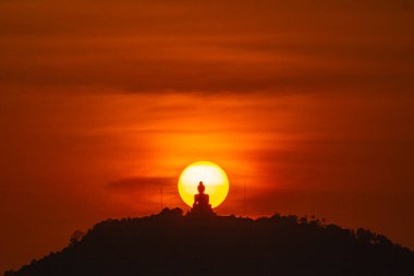 İnanılmaz kırmızı günbatımı gökyüzü ve Phuket büyük Buda sarı güneş çemberinde. Phuket, Tayland