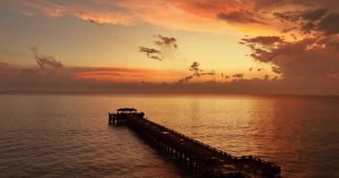 Gökyüzünün kırmızı rengini yansıtan deniz manzarası, video. Tayland, Phang Nga 'daki Natai iskelesi.