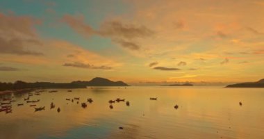 Sabah gökyüzündeki inanılmaz sarı bulutların havadan görünüşü. Güzel bir gün doğumu deniz manzarası. Rawai sahilindeki limanda tekneler, Phuket, Tayland 