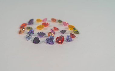 Farklı renklerde kalp şeklinde değerli taşlar daire şeklinde dizilmiştir. Güzelce kesilmiş ve cilalanmış doğal taş mineralleri değerli ve değerlidir. Renkli kalp şeklinde değerli taşlardır..