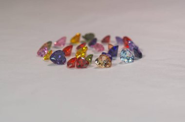 Farklı renklerde kalp şeklinde değerli taşlar daire şeklinde dizilmiştir. Güzelce kesilmiş ve cilalanmış doğal taş mineralleri değerli ve değerlidir. Renkli kalp şeklinde değerli taşlardır..