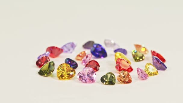 漂亮的多彩的心形钻石镶嵌在一个圆圈里各种颜色的心形钻石镶嵌在白色的地板上闪闪发光的钻石看上去迷人而美丽 — 图库视频影像