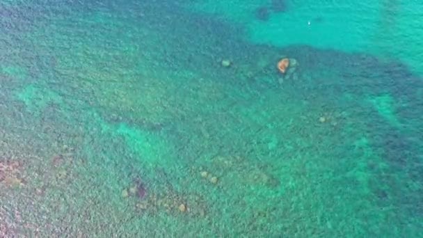 鸟瞰绿松石海旁边的岩石和山脚的绿林岛上周围的岩石与绿松石海的对比平静的海浪冲击着普吉岛的岩石岩石质感背景 — 图库视频影像