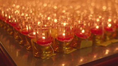 Sunak masasının üzerinde mum ışığı Bokeh. Turuncu-sarı gözlüklü mumlar, ayinler için türbelerdeki masaların üzerine konur. Geleneksel sebze festivali. Mum ışığı arkaplanı Bokeh.
