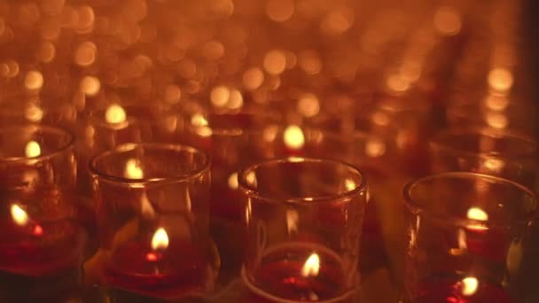 神殿の祭壇のテーブルにキャンドルライトのボケ オレンジ色のガラスのろうそくは儀式のために神社でテーブルの上に置かれます 野菜を食べる伝統的な祭り キャンドルライトの背景のボケ — ストック動画