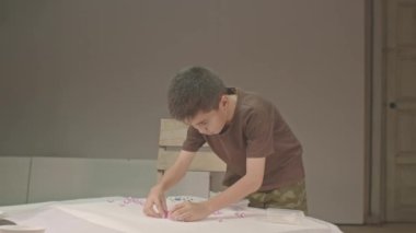 .Çocuk, stüdyoda yüksek kaliteli video 4K yapmak için elmasları dikkatlice kullanıyor. Stüdyo çekimi... renkli taşlarla oynamak çocukların öğrenmesi için harika bir yoldur. .. renkli mücevher arka planı.