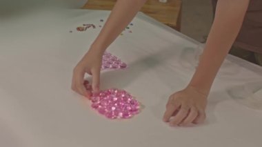 Çocuk stüdyoda yüksek kaliteli video 4K yapmak için elmasları dikkatlice kullanıyor. Stüdyo çekimi. Renkli mücevherlerle oynamak çocukların öğrenmesi için harika bir yoldur. Renkli mücevher geçmişi.