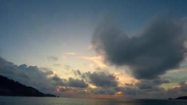 Günbatımının ya da güneşin doğuşunun hızlandırılmış manzarası. Fantezi bulutları Patong plajı üzerinde sarı günbatımı Phuketi ile kaplanıyor. Adaların üzerinde güneş ışığı parlıyor..