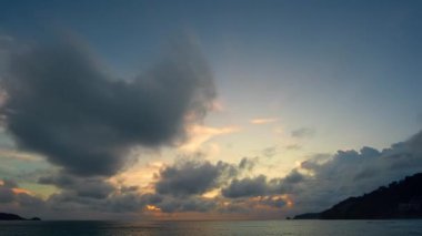 Günbatımının ya da güneşin doğuşunun hızlandırılmış manzarası. Fantezi bulutları Patong plajı üzerinde sarı günbatımı Phuketi ile kaplanıyor. Adaların üzerinde güneş ışığı parlıyor..