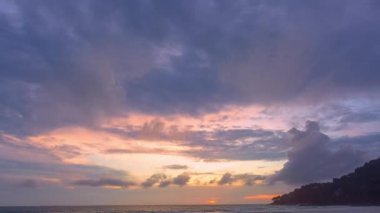 Günbatımının ya da güneşin doğuşunun hızlandırılmış manzarası. Fantezi bulutları Patong plajı üzerinde sarı günbatımı Phuketi ile kaplanıyor. Adaların üzerinde güneş ışığı parlıyor..