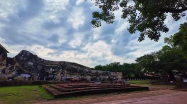 .Dini Tarih Parkı 'ndaki uzanan Buda heykelinin üzerindeki mavi gökyüzünde beyaz bulutlar. Gün doğumu manzarası. Tapınak harabe ama Buda tamamen mükemmel..