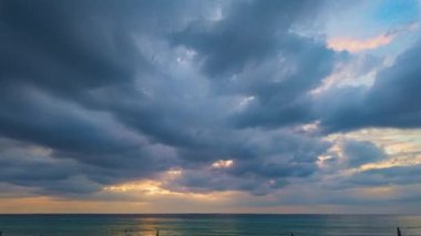 Zaman atlamalı bulutlar gün batımında denizin üzerinde yüzerler. Batan güneş tarafından aydınlatılan bulutlar güzel ve sakin bir atmosfer yaratır. Anın güzelliği nefesini keser.