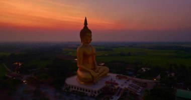Dünyanın en büyük Buda heykelinin alacakaranlıkta kırmızı gökyüzü... kırmızı atmosfer arkaplanı... pirinç tarlasında altın büyük Buda... Wat Muang Ang tangası Tayland 'ın popüler simgesi.