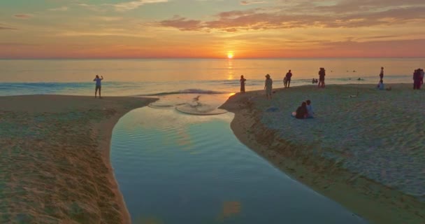 砂浜の風の運河の空中ビュー 観光客は砂浜の小さな運河のそばに置かれた太陽を見ます Bubble波と明確な砂の風景に美しい空の反射 — ストック動画