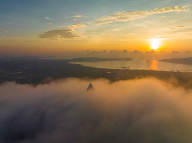 Aerial view The golden sun shines through the clouds above the ocean at the Big Buddha...bright yellow sun ray shine on the head of Phuket big Buddha. ..The sun's rays were peeking through the clouds.