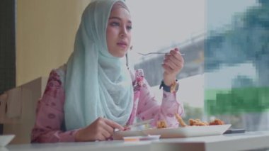 Güzel İslam kadını kızarmış tavuk yiyor. İslam kadını Tayland 'ın Bangkok şehrinin yanındaki restoranda kızarmış tavuk yiyor.