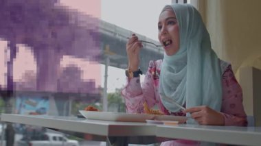 Güzel İslam kadını kızarmış tavuk yiyor. İslam kadını Tayland 'ın Bangkok şehrinin yanındaki restoranda kızarmış tavuk yiyor.
