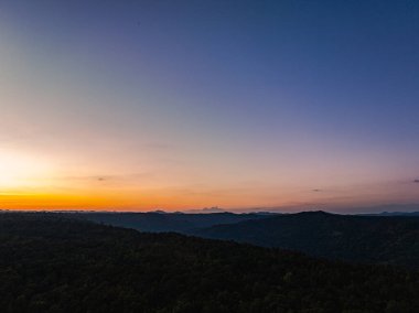 Dağların üstündeki renkli gökyüzü ile günbatımının havadan görünüşü 